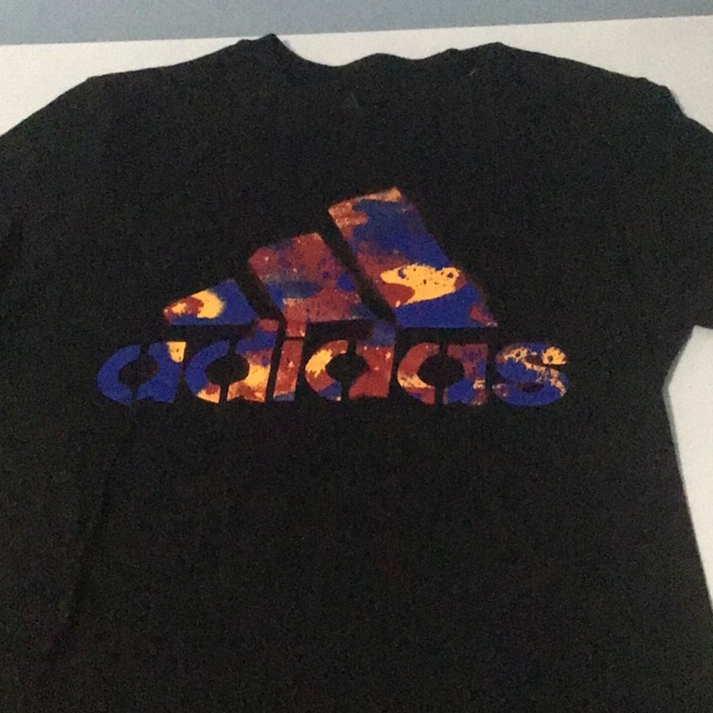 Small unisex t-shirt in black, with a color splashes spelling adidas.